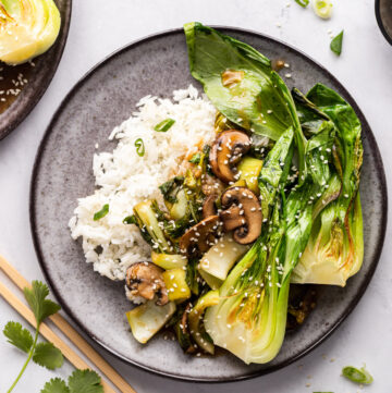 Plate of bok choy stir fry with mushrooms on rice.