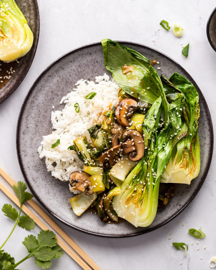 Plate of bok choy stir fry with mushrooms on rice.