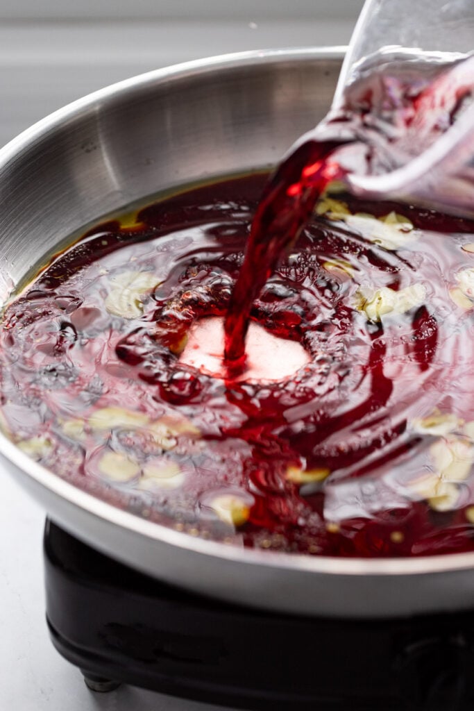 Red wine pouring into skillet.