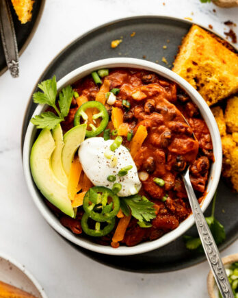Bowl of chili with toppings and spoon.