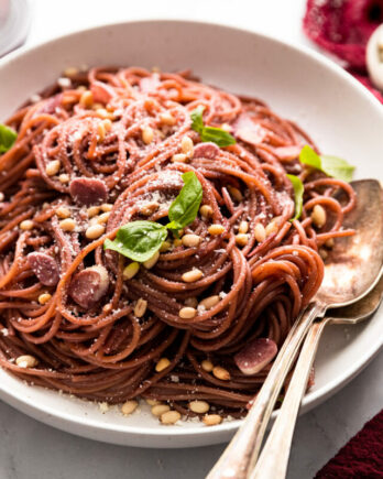 Bowl of red wine pasta with serving spoons.