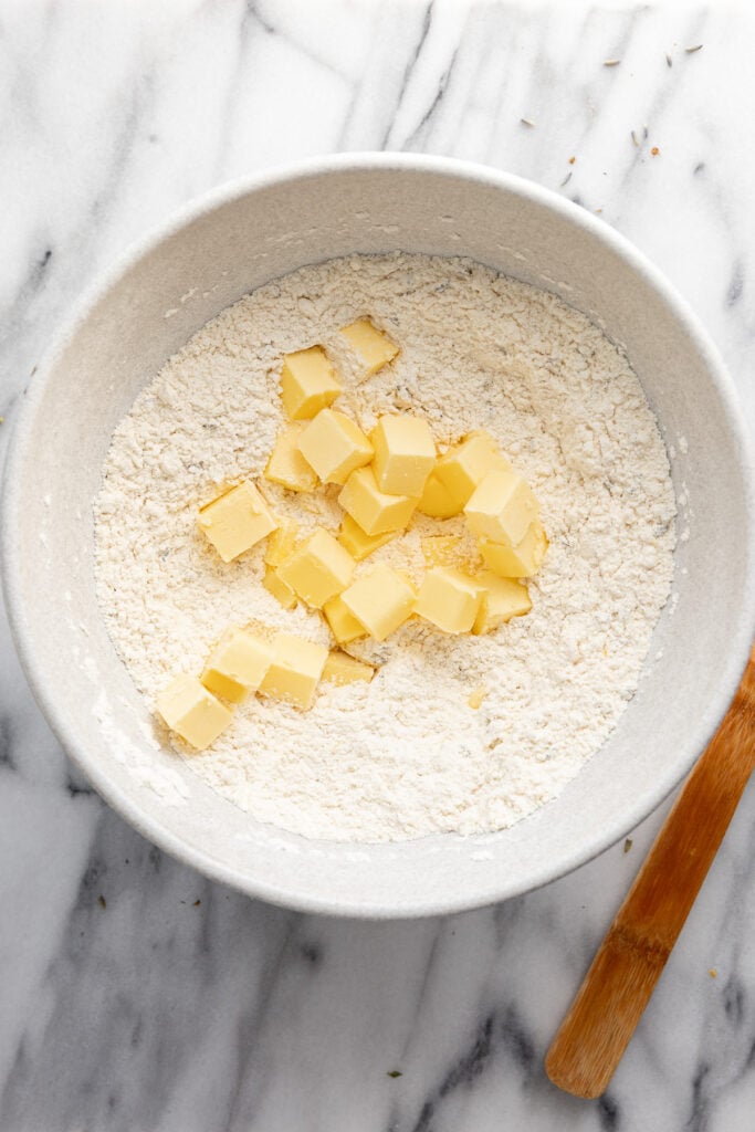 Dry ingredients in bowl with cubes of butter.