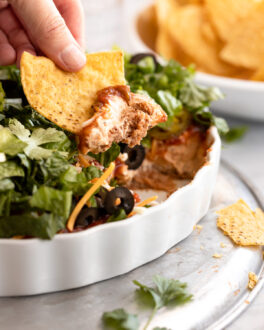 Hand with chip with taco dip.
