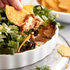 Hand with chip with taco dip.