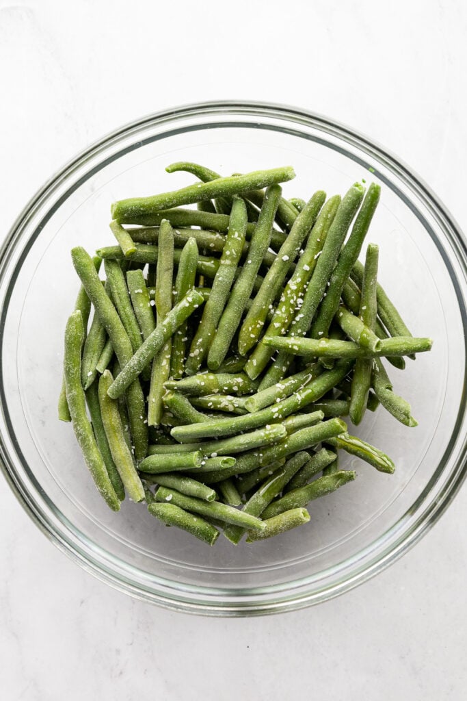 Frozen green beans in glass bowl with salt.