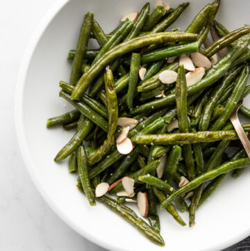 White bowl with green beans and almonds.