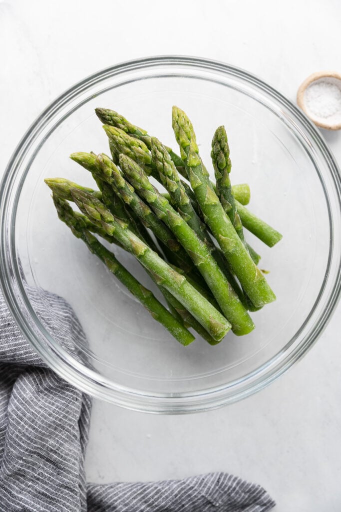 Frozen asparagus spears in glass bowl.