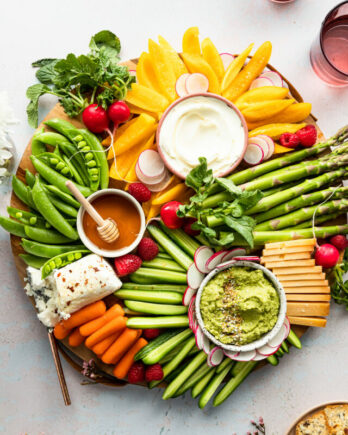 Spring inspired board with fresh veggies, cheese, and dips.