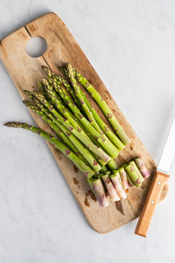 Fresh asparagus on cutting board with ends cut off.