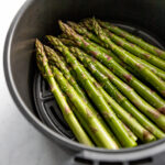 Fresh asparagus in air fryer with shine from a little oil.