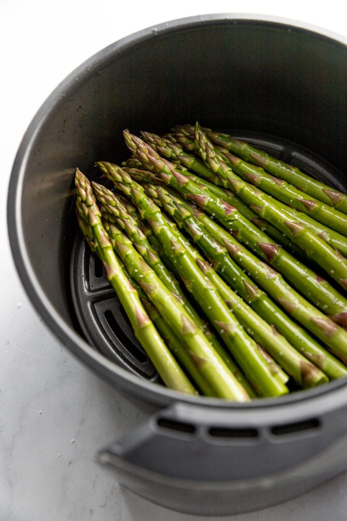 Fresh asparagus in air fryer with shine from a little oil.