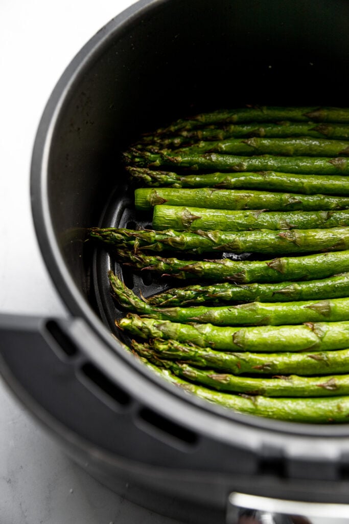Asparagus in basket of air fryer after cooking.
