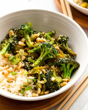Broccoli stir fry in white bowl next to chopsticks.