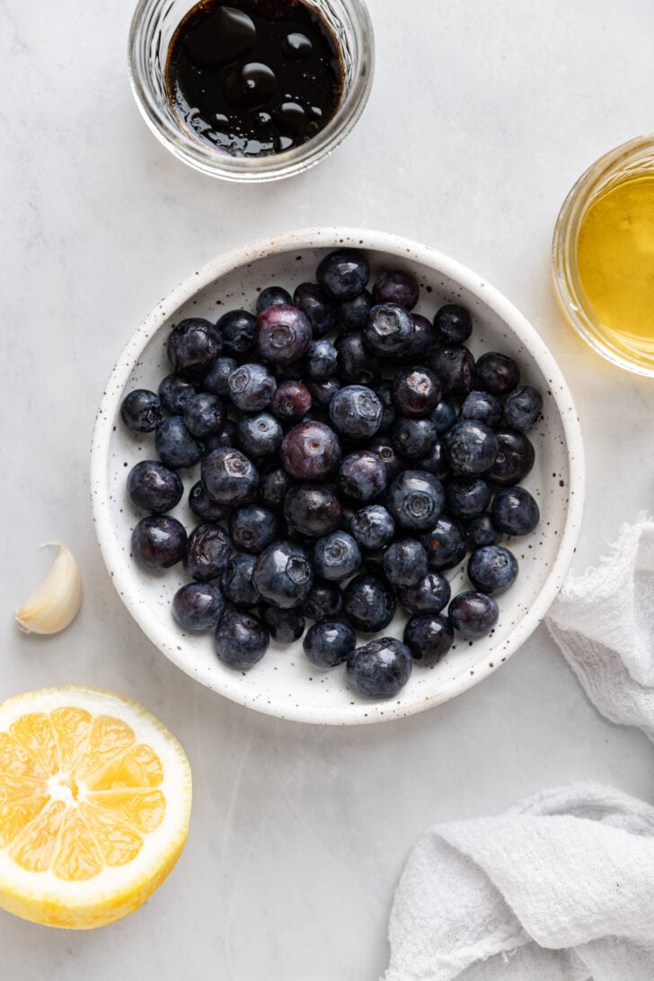 Bowl of blueberries next to lemon, oil, and balsamic vinegar.
