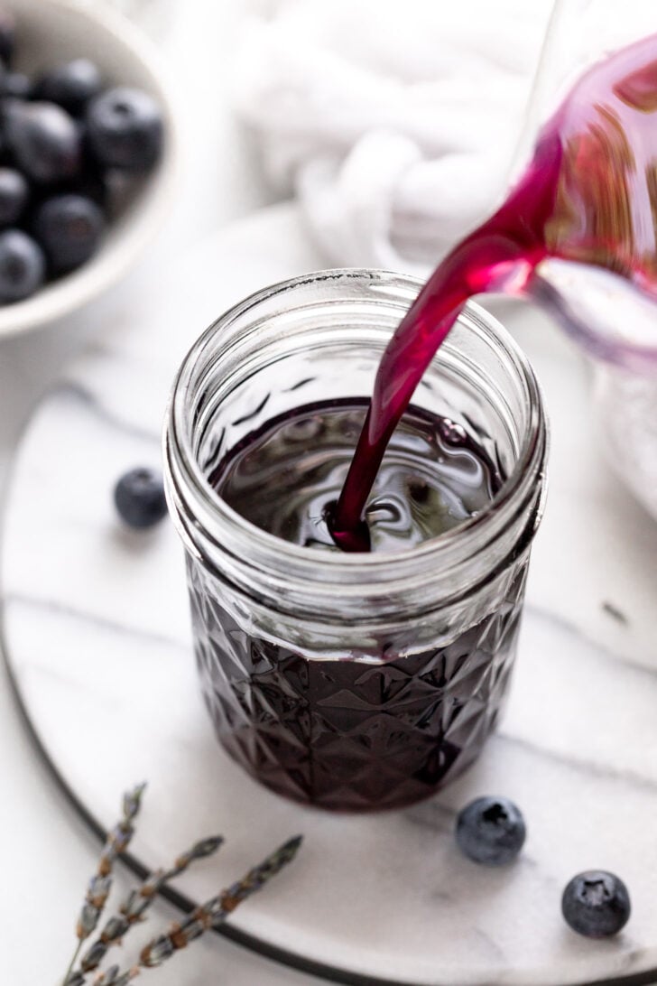 Blueberry lavender syrup pouring into jar.