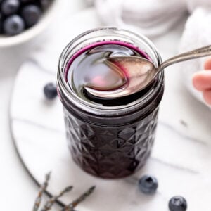 Jar of blueberry lavender syrup with spoon scooping out.