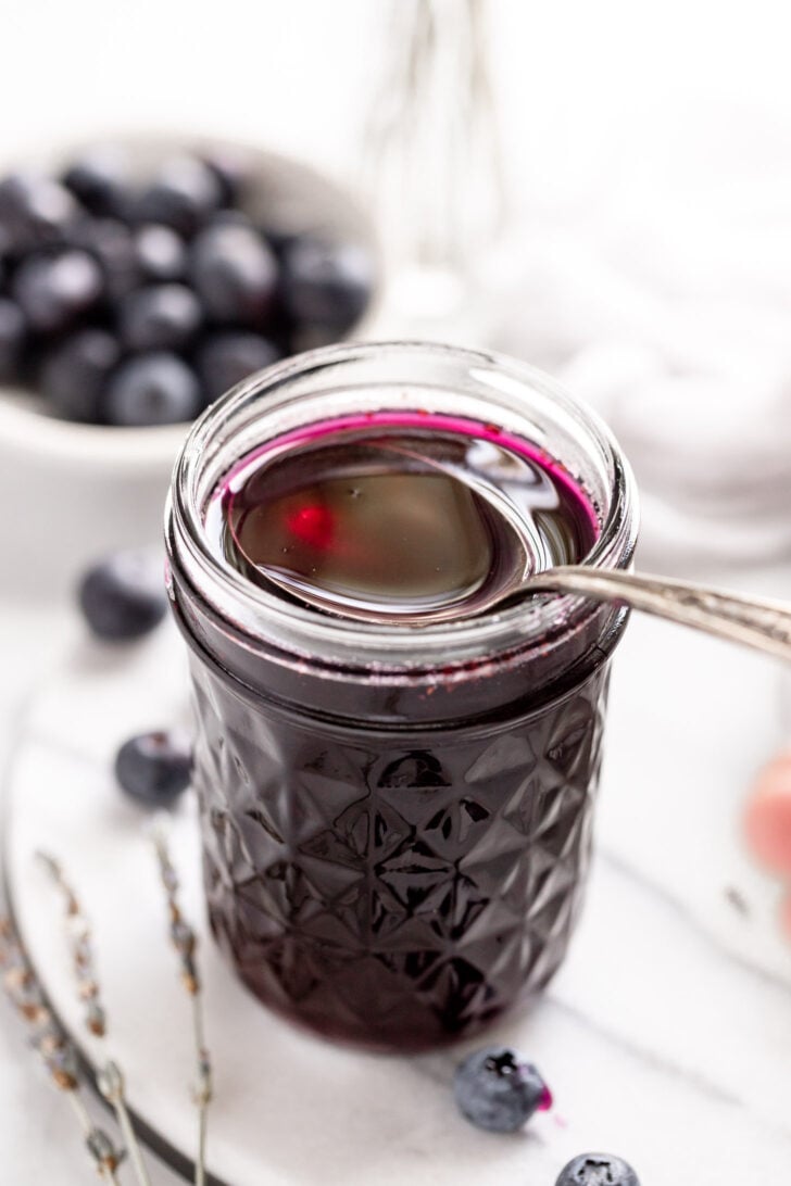 Jar of blueberry lavender syrup with spoon.