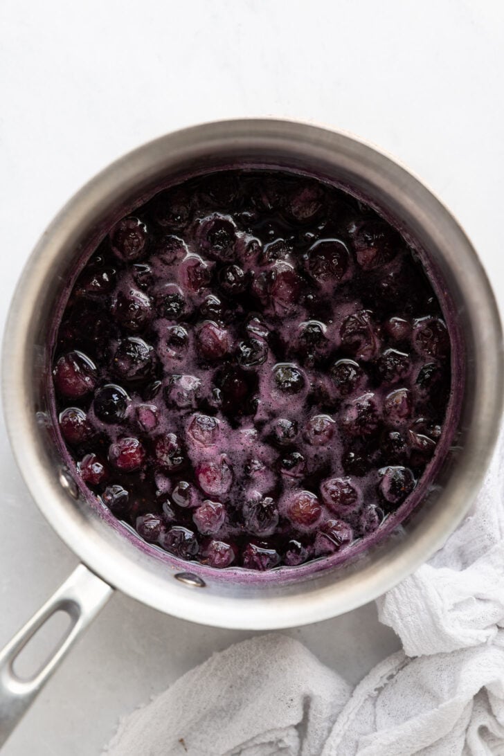 Saucepan with smashed blueberries in sauce.