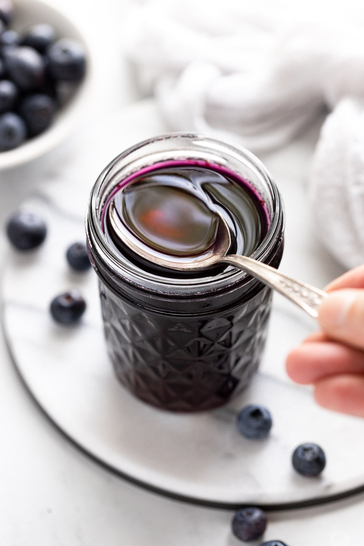 Spoon scooping blueberry syrup.