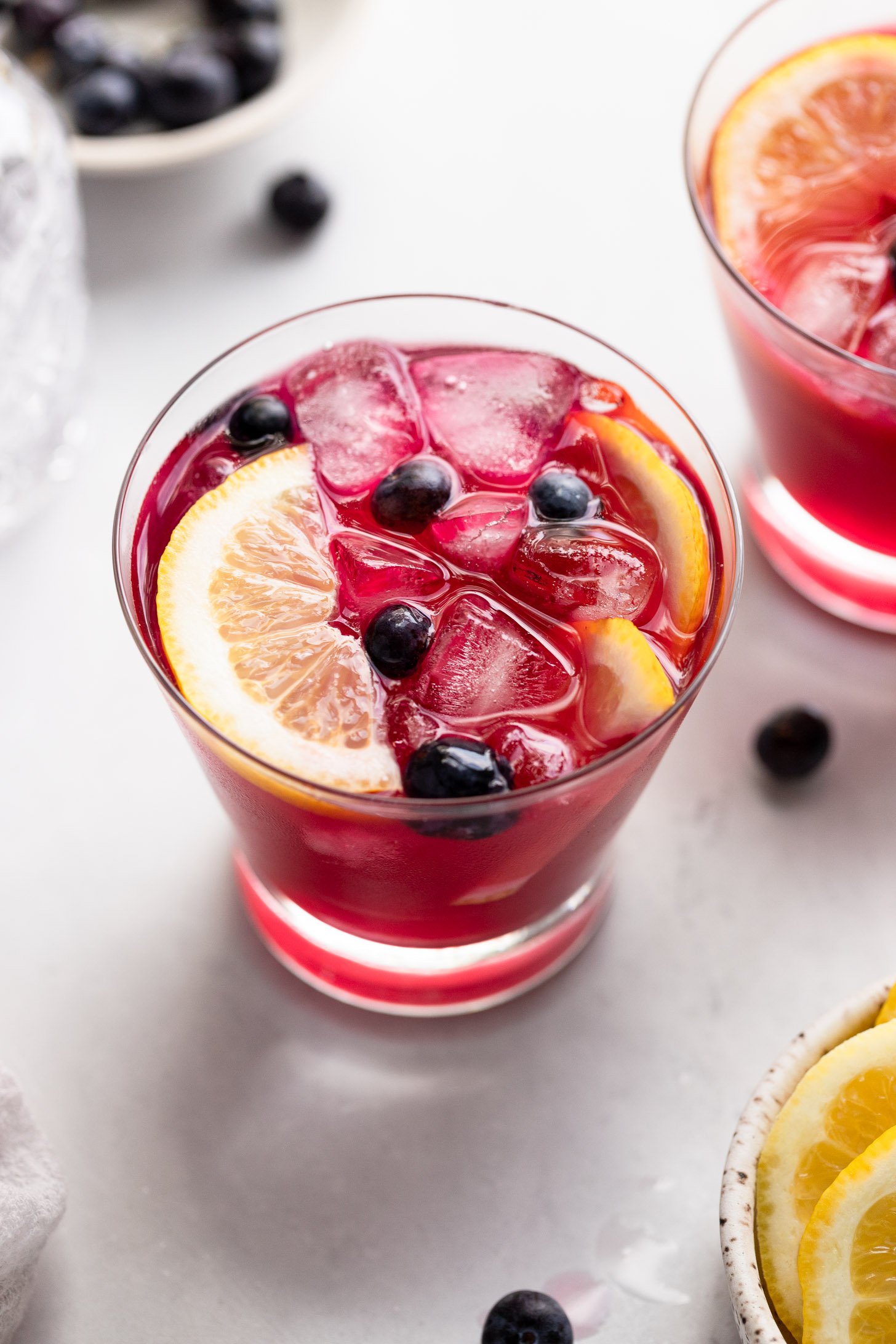 Glass of blueberry vodka lemonade with garnishes.