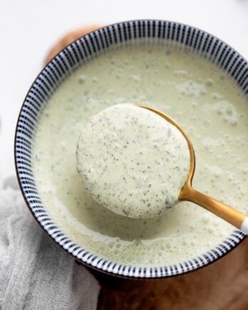Spoon scooping cilantro lime sauce from bowl.