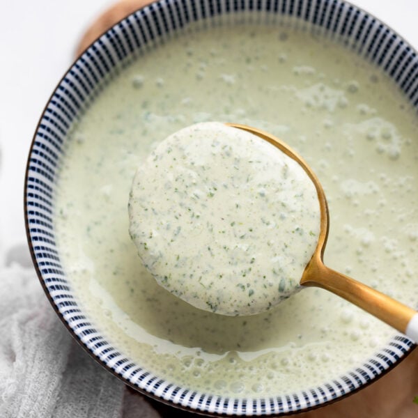 Spoon scooping cilantro lime sauce from bowl.