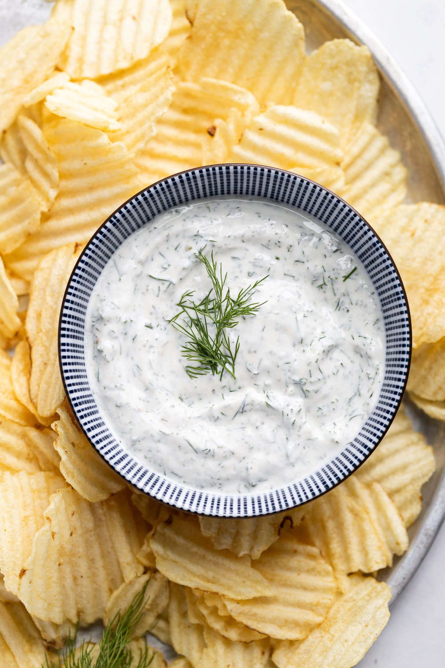 Tray of chips with dill sauce in bowl in middle.