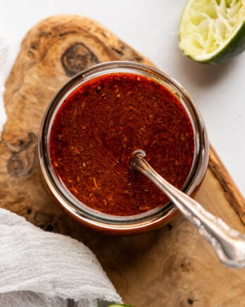 Fajita sauce in jar with spoon next to limes.