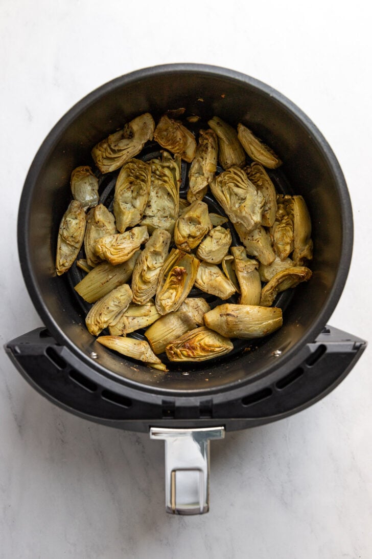 Air fryer basket with frozen artichoke hearts after cooking.