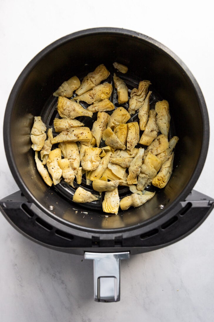 Canned artichoke hearts in air fryer before cooking.