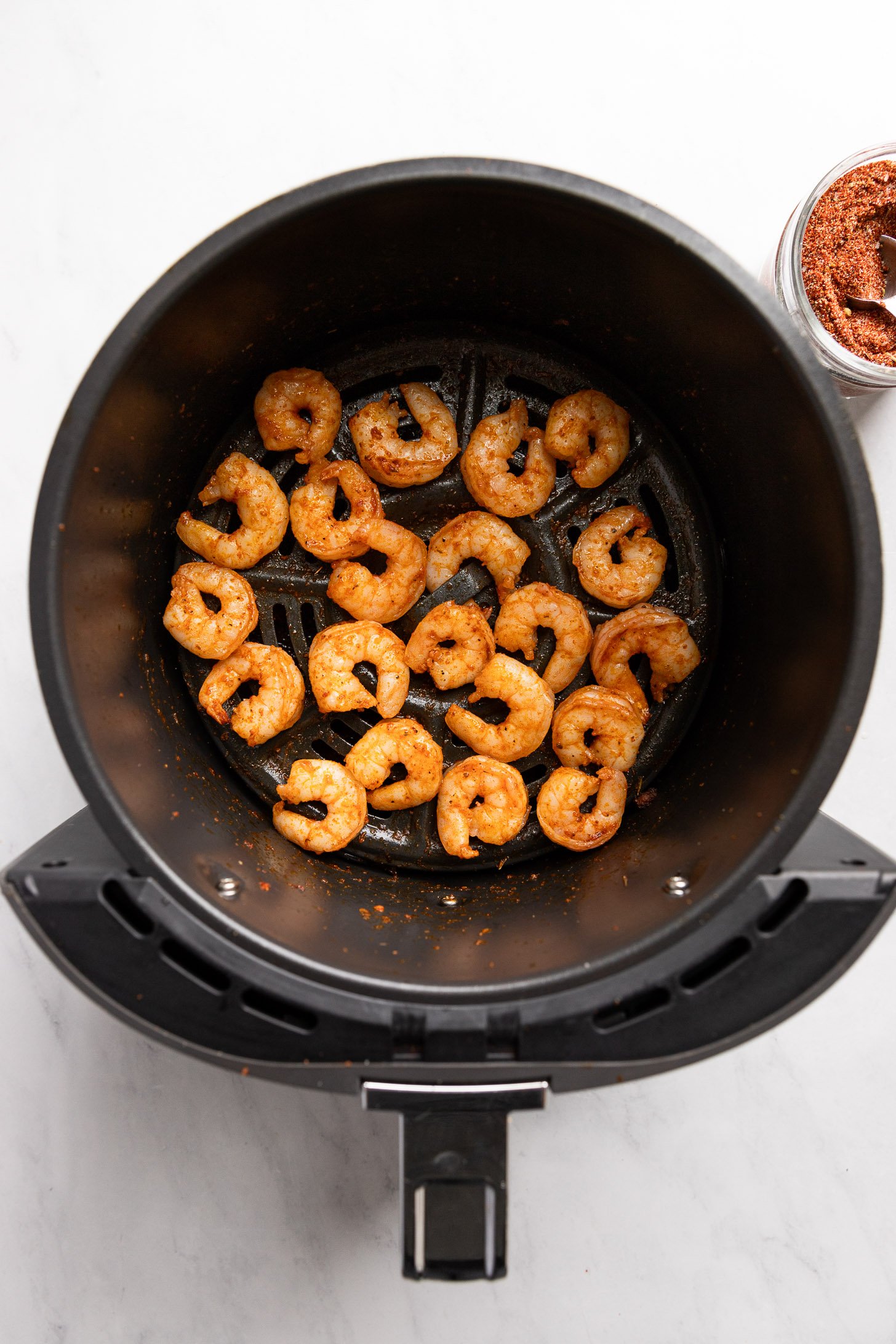 Cajun shrimp in air fryer basket after cooking.