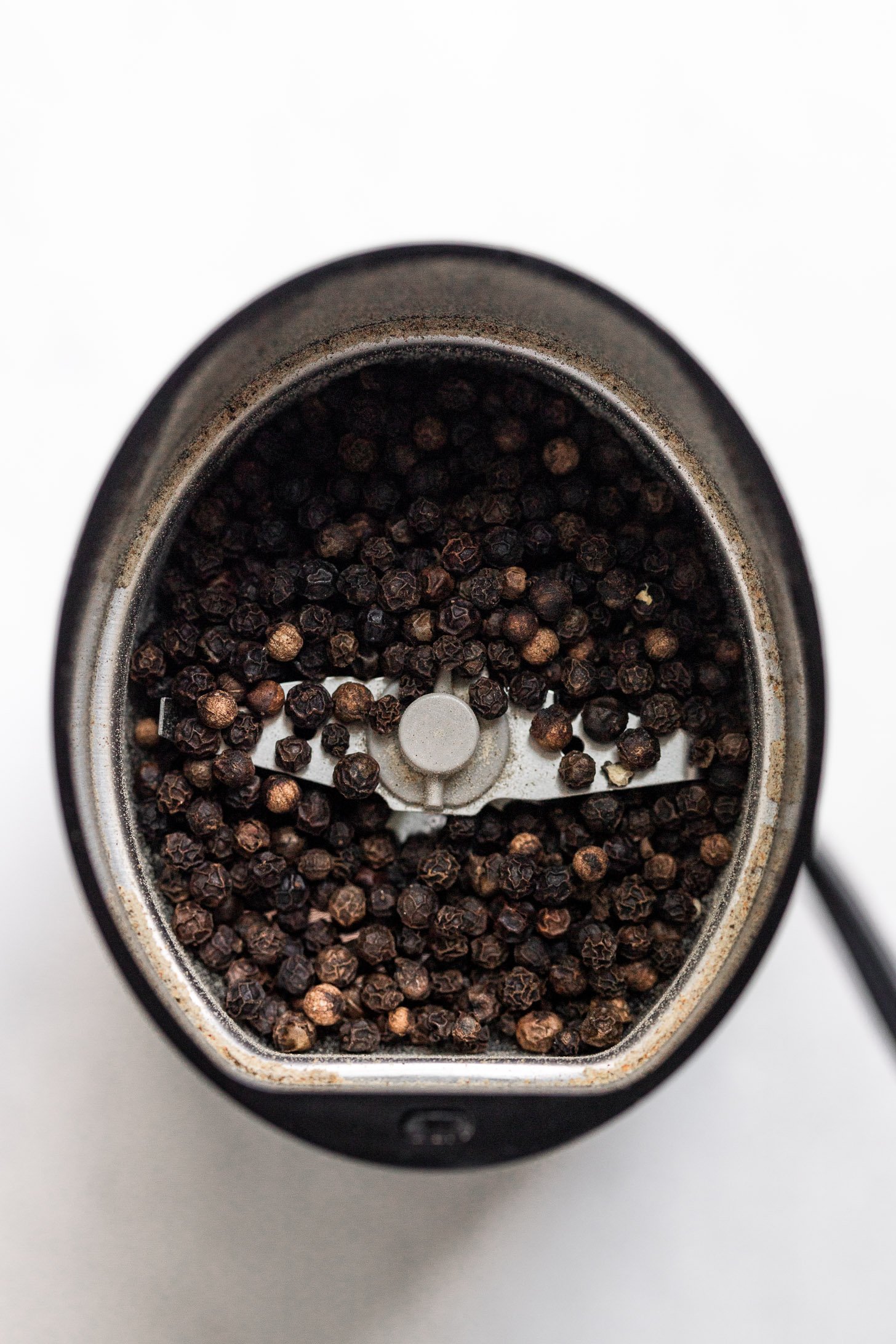Peppercorns in spice grinder.