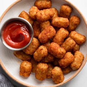 Plate of air fryer frozen tater tots with little bowl of ketchup.