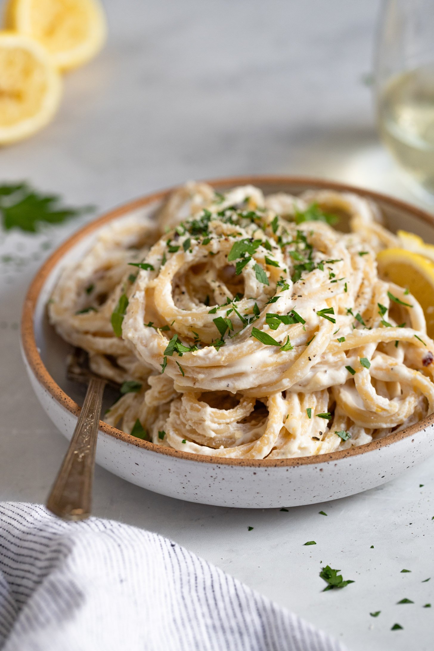 Side view of bowl of lemon pasta with garnish.