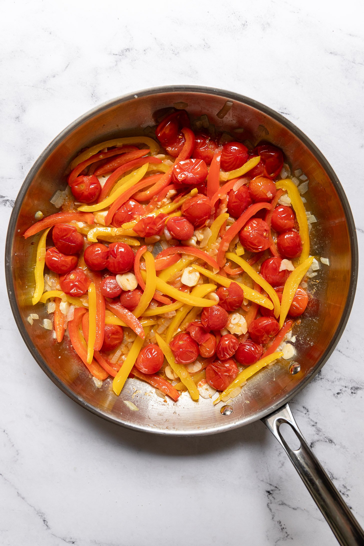 Bell Peppers, tomatoes, and garlic in skillet.