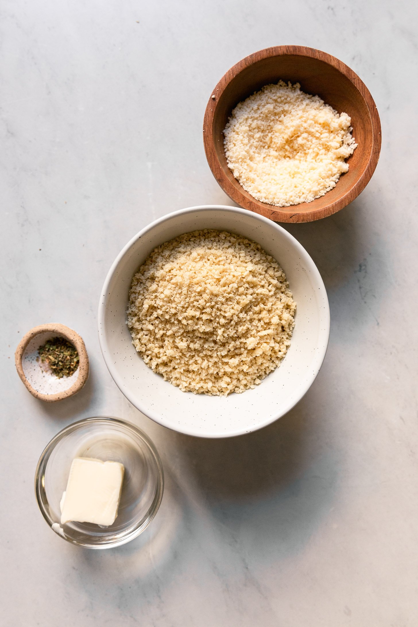 Panko, spices, grated parmesan cheese, and butter in bowls.