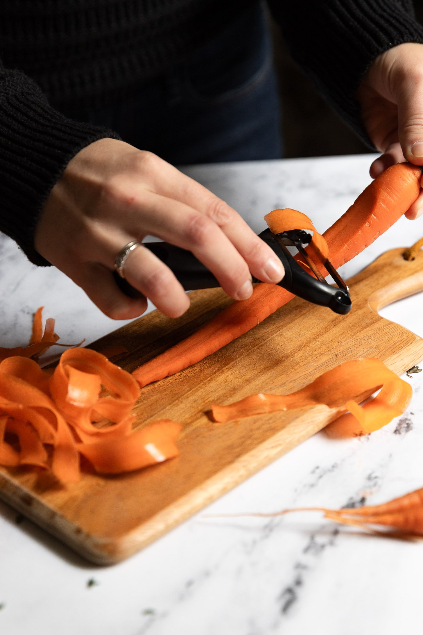 Hand using Y-peeler to make thin strips of carrots.