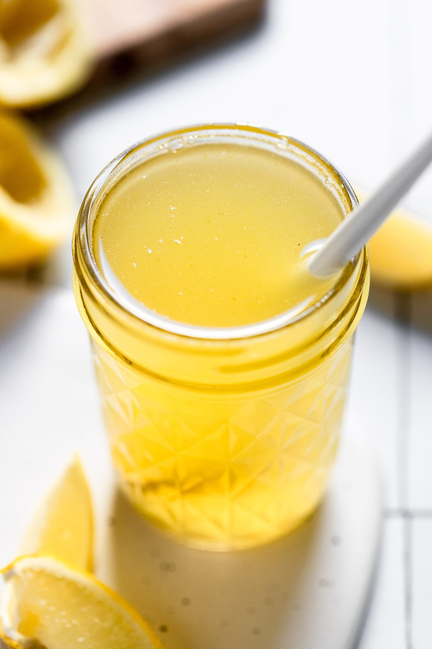 Jar of lemon syrup with spoon inside.