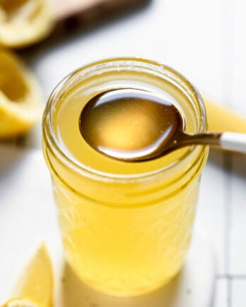 Jar of lemon simple syrup with spoon scooping out.