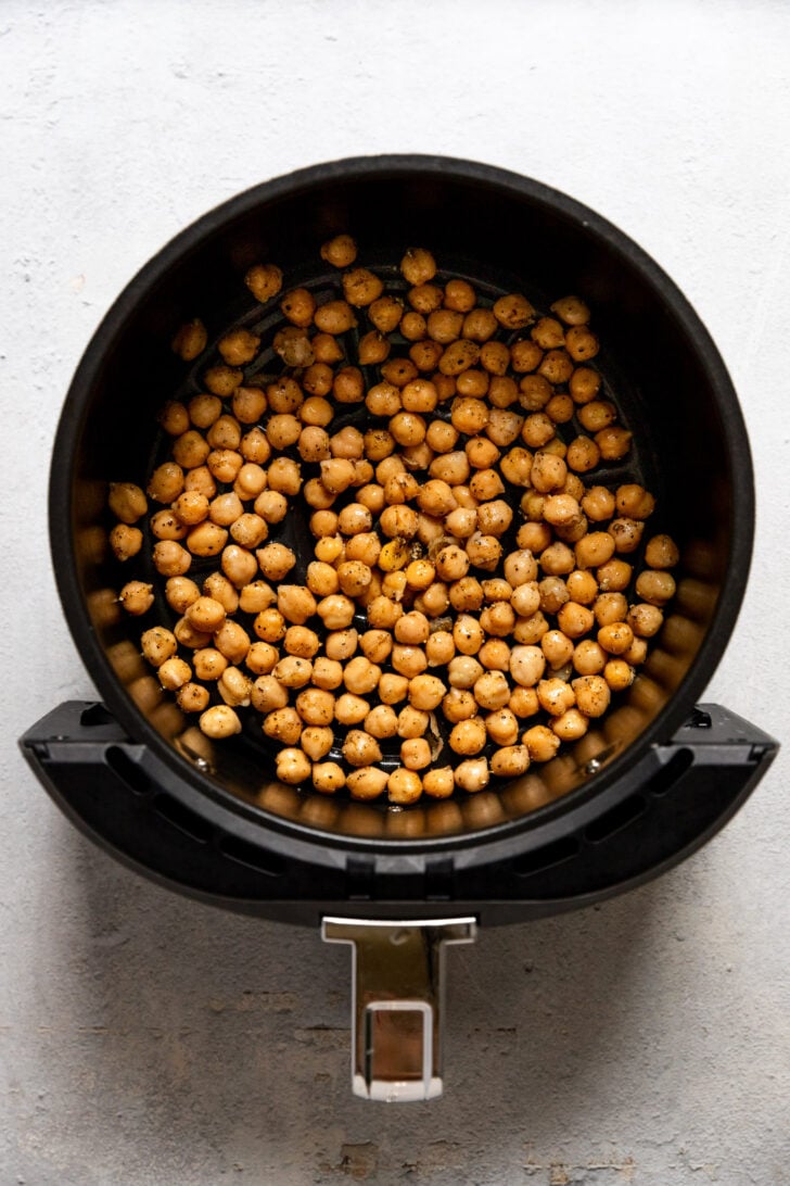 Air fryer basket with chickpeas before cooking.