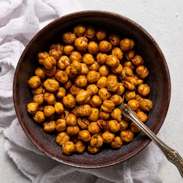 Bowl of air fryer chickpeas with spoon ned to linen.