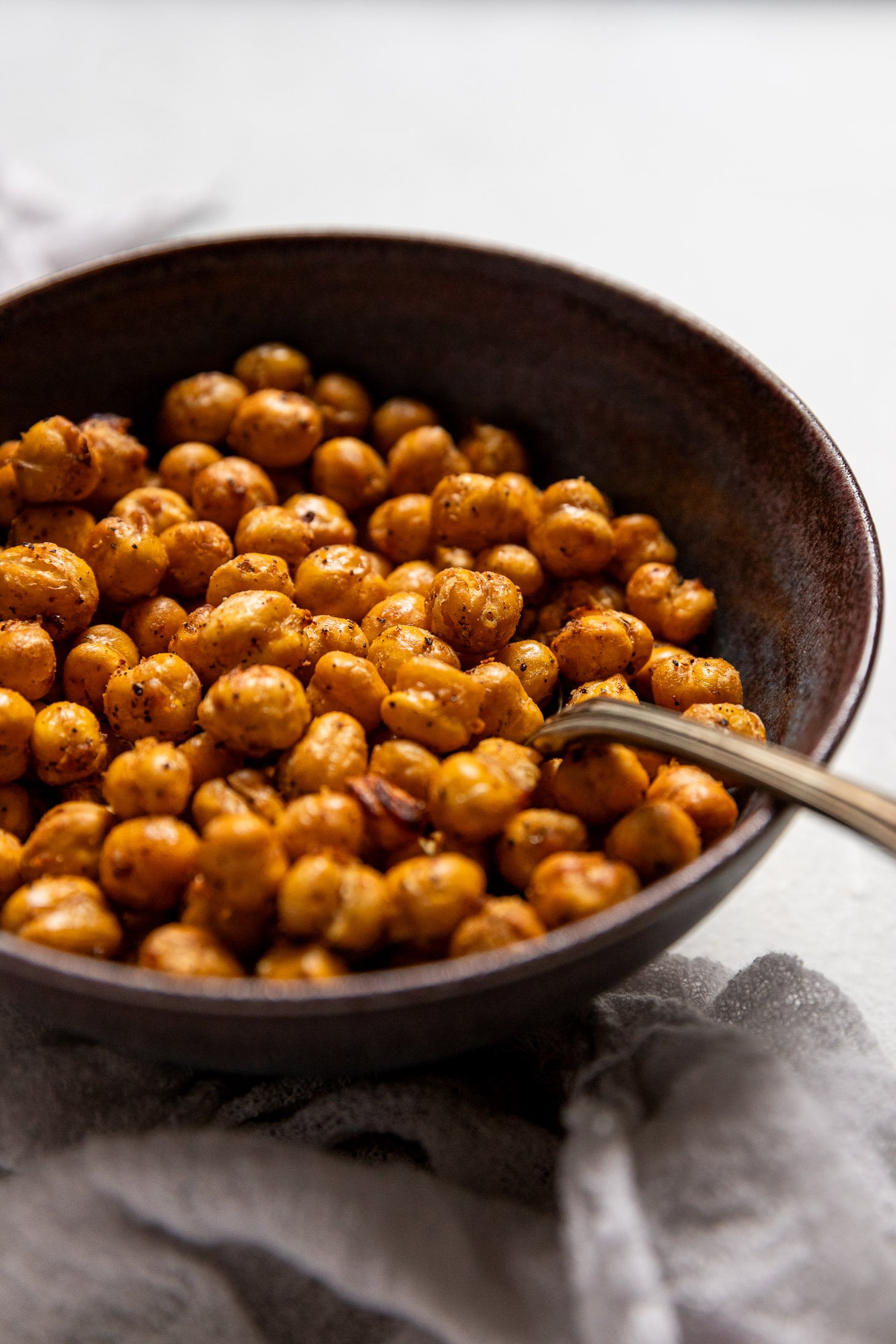 Side view of spoon in bowl of crispy chickpeas.