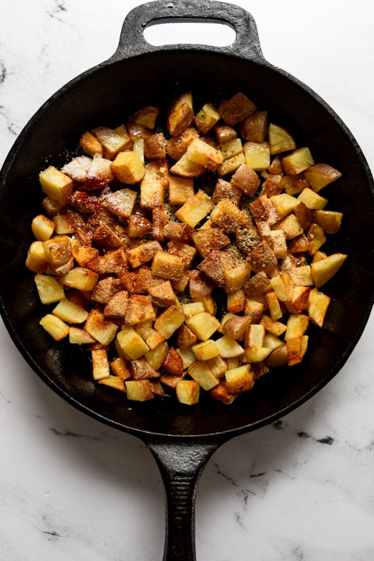 Spices in skillet with potatoes.