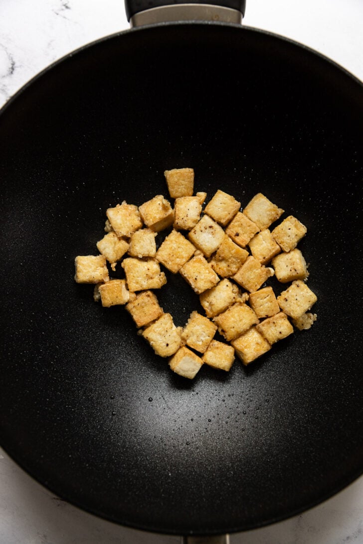 Wok with golden brown tofu cubes.