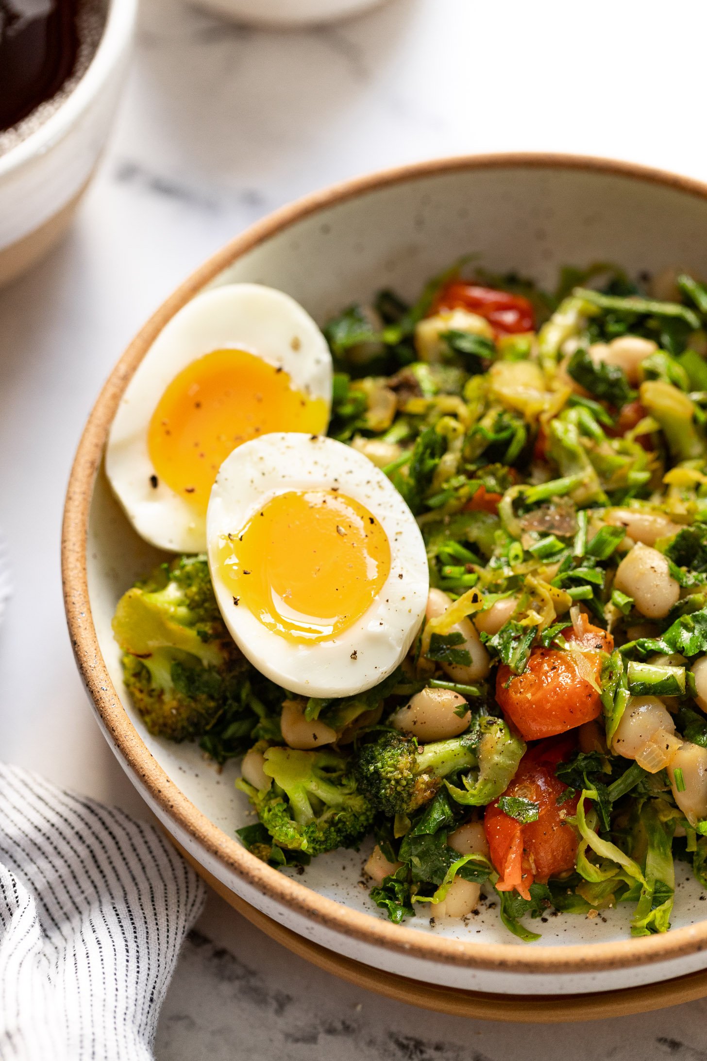 Soft boiled eggs on top of bowl of breakfast vegetables.
