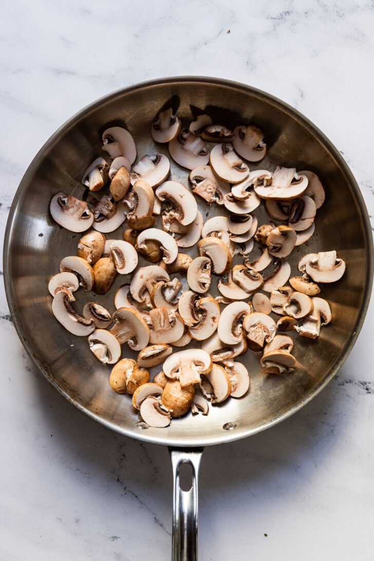 Raw sliced mushrooms in skillet.