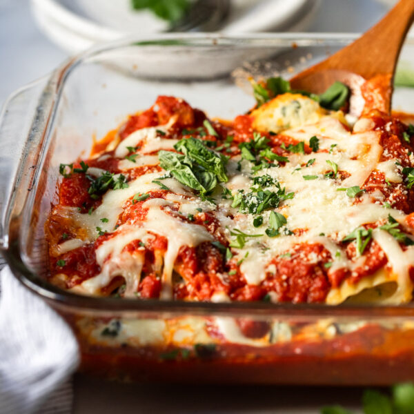 Cheese manicotti in baking dish with serving spoon.