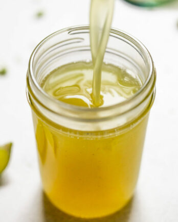 Lime simple syrup pouring into jar.