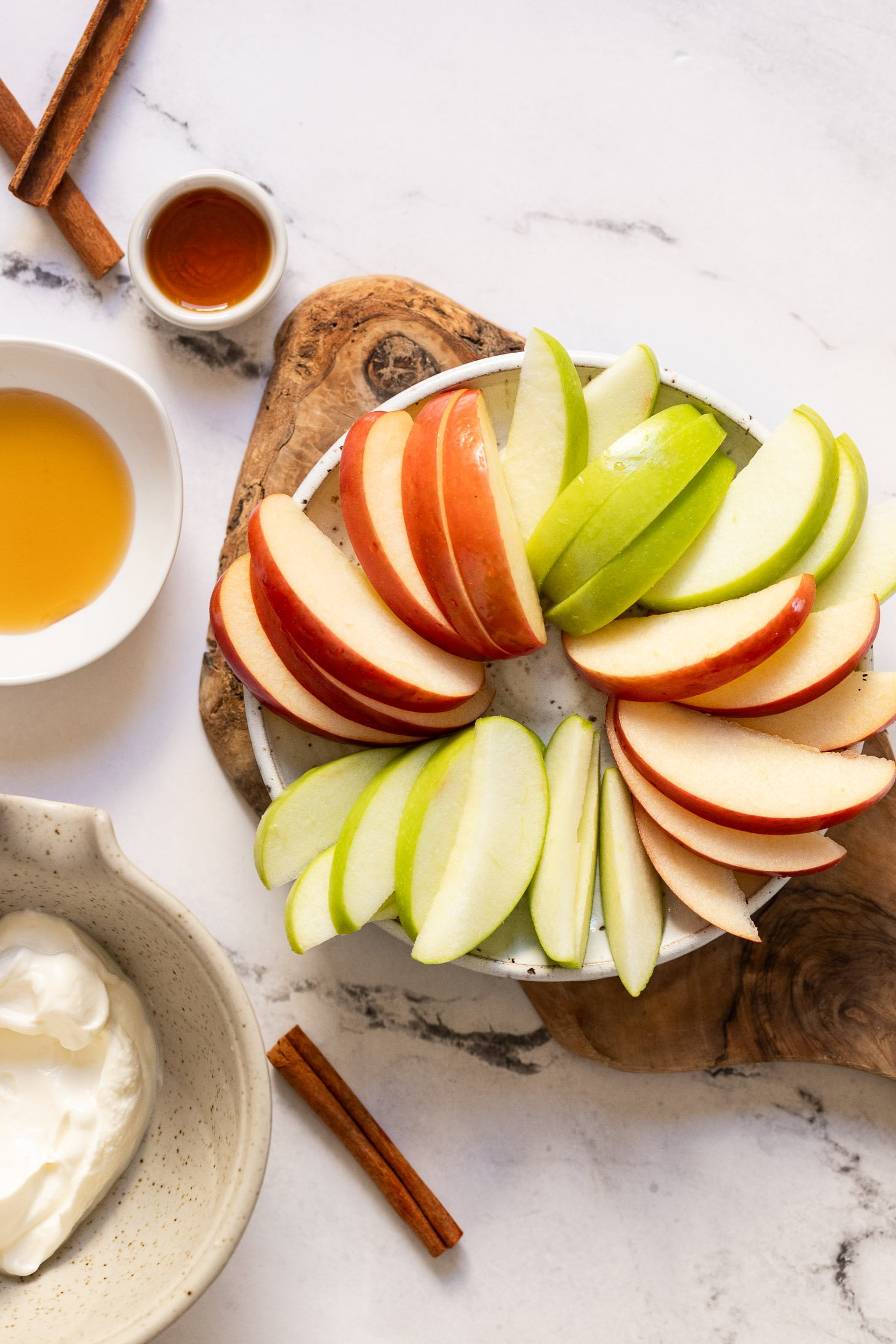 Apple slices on plate next to bowls of ingredients.