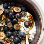 Spoon in bowl with cottage cheese and blueberries.